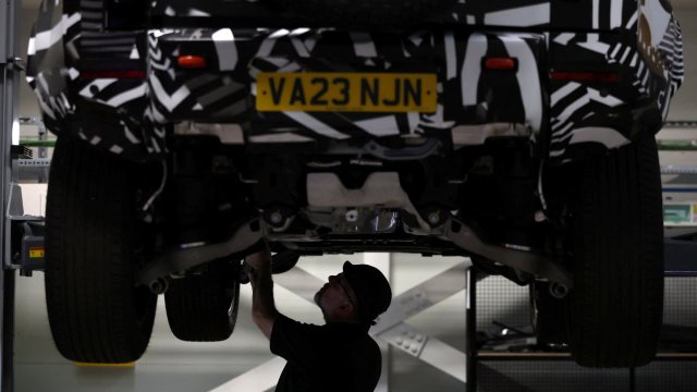 Article thumbnail: An engineer works below a Land Rover Defender mild hybrid electric vehicle at the new Jaguar Land Rover electric vehicle test centre in Whitley, Britain, October 23, 2023. REUTERS/Phil Noble