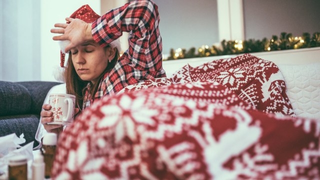 Article thumbnail: Girl dressed for christmas drinking tea in bed, feeling sick and tired, trying to get better.